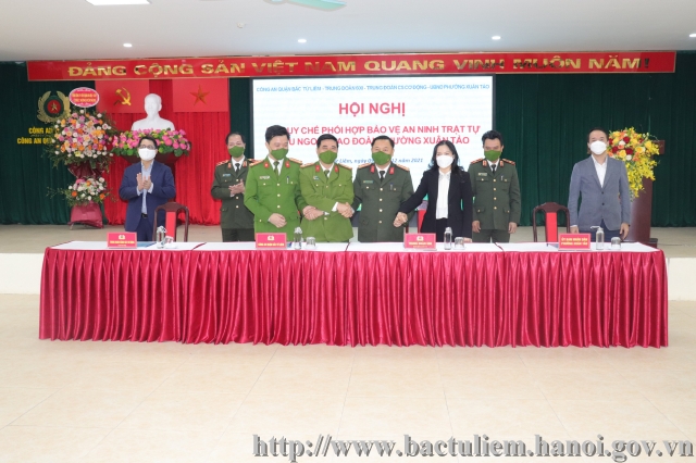 Description: A group of people standing behind a table with a red tableclothDescription automatically generated with low confidence