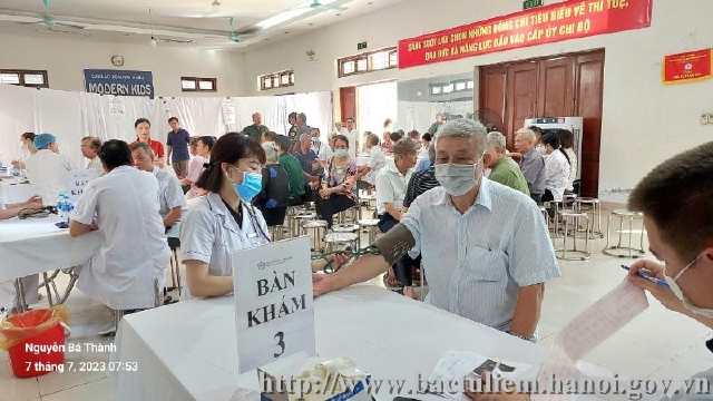 A person wearing a face mask standing at a table with a signDescription automatically generated